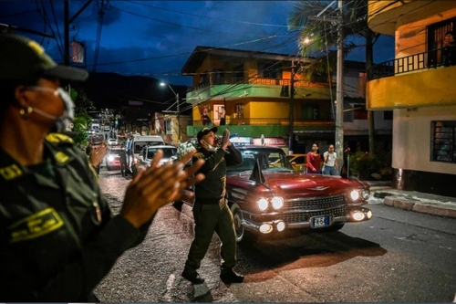 پلیس کلمبیا در حال خواندن اطلاعیه هشدار شیوع ویروس کرونا در خیابانی در شهر